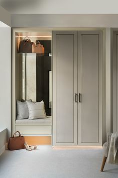 a bedroom with white carpet and gray cabinets in front of a window, purse on the floor