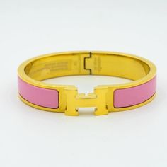 a yellow and pink bracelet on a white surface with the letter h in it's center