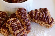 chocolate covered cookies sitting on top of a white plate next to a bowl of cereal