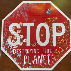 a stop sign with the words destroying the planet painted on it