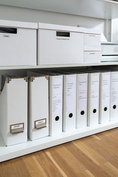 some white file cabinets are stacked on top of each other in a room with hard wood flooring