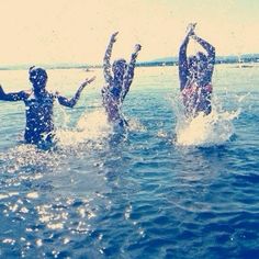 three people are splashing in the water while holding hands up to their chests and arms