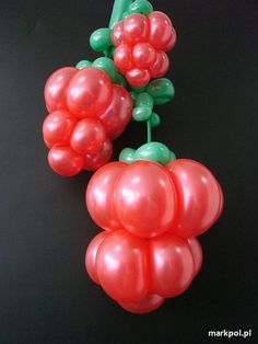 two bunches of red and green balloons on a black surface with one balloon attached to the other