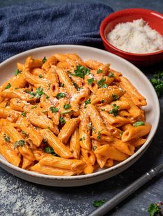 pink sauce pasta in a white bowl with parsley on top and the words, pink sauce pasta