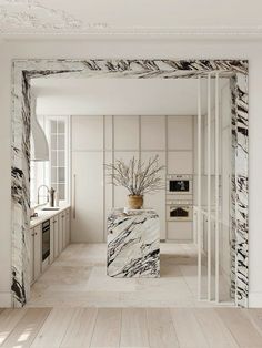 a white kitchen with marble counter tops and cabinets in the corner, along with a plant