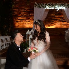 a man kneeling down next to a woman in a wedding dress