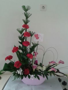 a flower arrangement in a pink bowl on a table