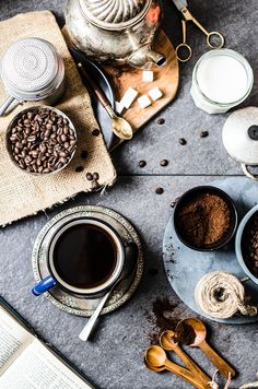 two cups of coffee on a table with spoons and other items around them,