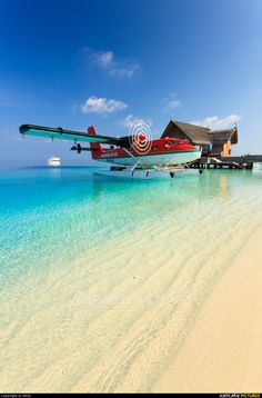 an airplane sitting on top of a sandy beach next to the ocean with clear blue water