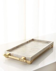 a marble tray with gold handles on a white counter