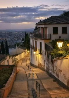 an alley way with stairs leading up to buildings and lights on the side of it