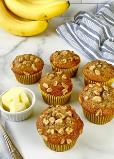 several muffins with walnuts and butter next to some bananas