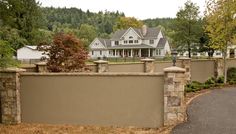 a large house behind a stone fence with trees in the background