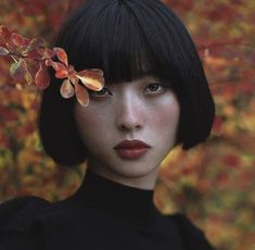 a woman with short black hair and flowers in her hair is looking at the camera