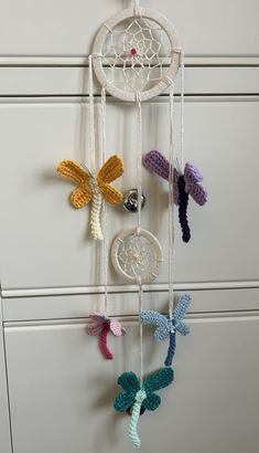 a crocheted dream catcher hanging on the wall next to a cabinet with drawers