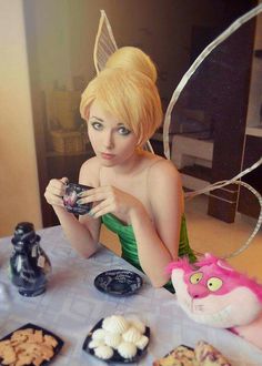 a woman dressed as tinkerbell sitting at a table with cookies