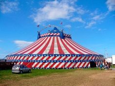 a large circus tent with an american flag design on the side and a car parked in front