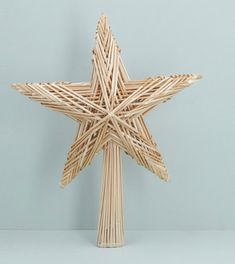 a wooden star shaped object made out of sticks on a white surface with a light blue wall in the background