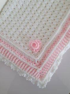 three crocheted baby blankets with pink and white trims on the edges are folded together