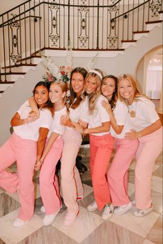 a group of women standing next to each other in front of a stair case with flowers on it