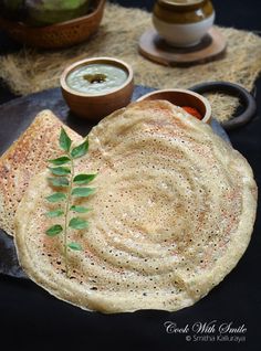 some food is on a black plate with sauces and spoons next to it