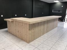 an empty room with a large wooden counter in the center and black walls behind it