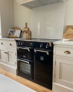 a black stove top oven sitting inside of a kitchen next to white cabinets and drawers