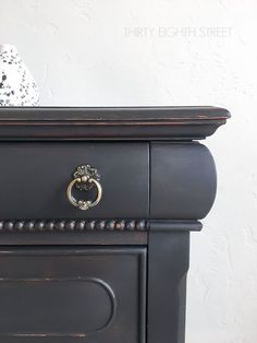 a black dresser with an ornate handle on it