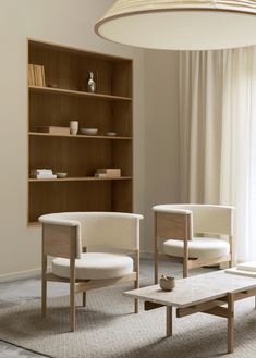 a living room with two chairs and a coffee table in front of a book shelf