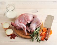 raw chicken on a cutting board with carrots, onions and spices