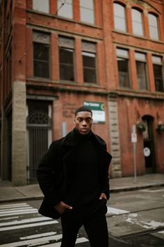 a man standing in front of an old brick building on the corner of a street