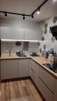 a kitchen with white cabinets and wood floors is pictured in this image, there are lights above the sink