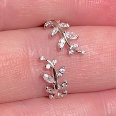 a close up of a person's hand with two rings on their fingers and one ring in the shape of a leaf