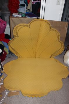 a large yellow shell shaped chair sitting on the floor