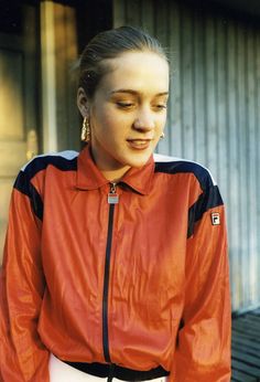 a woman wearing a red jacket and black pants standing in front of a garage door