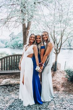 three women standing next to each other in front of a tree