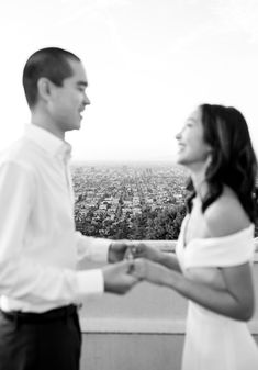 a man and woman standing next to each other in front of a cityscape