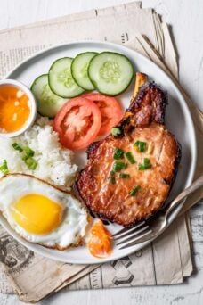 a white plate topped with meat, rice and veggies next to a fork