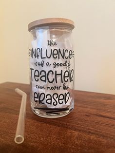 a glass jar with writing on it sitting on top of a table next to a straw