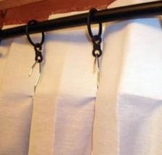 two pairs of scissors hanging from the side of a curtain with black handles on it