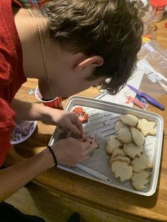 a boy is making cookies on a tray