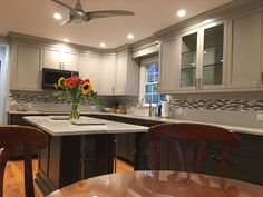 a kitchen with wooden chairs and an island in the middle of it, surrounded by gray cabinets