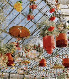 many hanging glass balls and plants in an indoor garden area with flowers on the ceiling