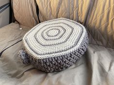 a crocheted round ottoman sitting on top of a bed next to a pillow