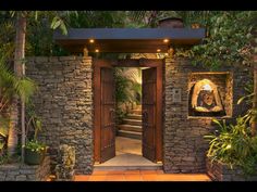 an entrance to a house with stone walls and doors leading into the garden area at night