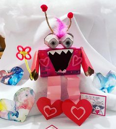 a valentine's day card with a paper monster holding two heart shaped candy boxes