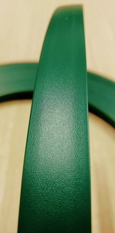 a close up of a green ribbon on a wooden table with wood grained surface