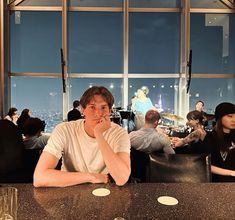 a man sitting at a table in front of a window with people eating and drinking