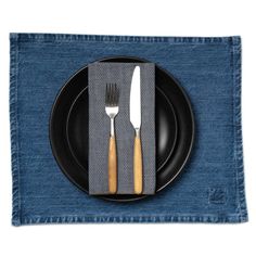 a black plate topped with two forks and a knife next to a blue place mat