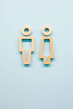 two wooden cutouts of people standing next to each other on a light blue background